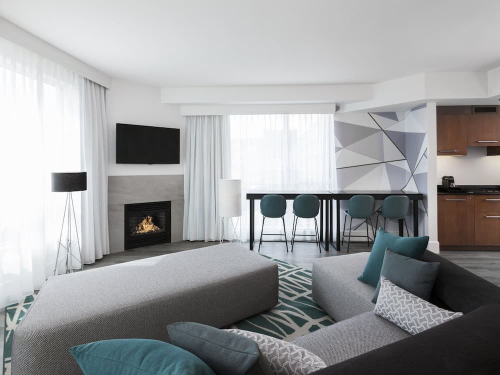 A living room with a table, chairs, and a view of Montreal city.