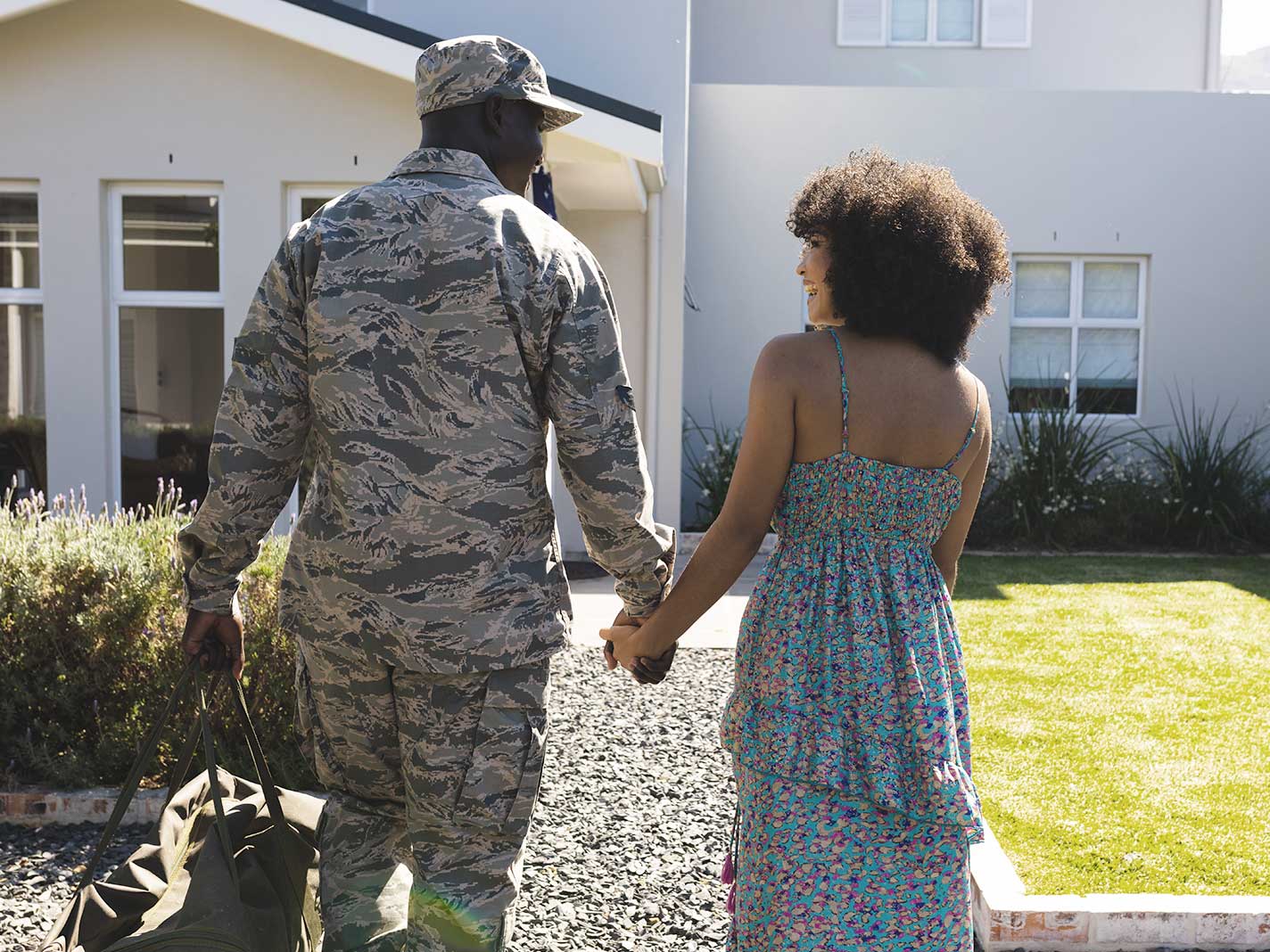 Military couple holding hands outside of a house