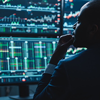 Person analyzing multiple data screens with stock charts.