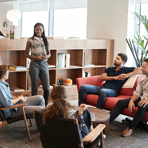 Person standing and presenting to casual group seated in modern office lounge area