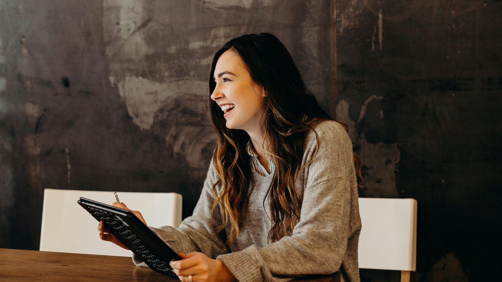 Person holding a tablet while sitting at a table