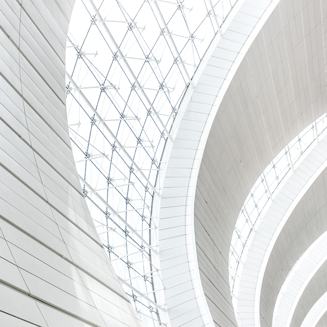 Modern white architectural interior with curved glass ceiling and geometric support structure