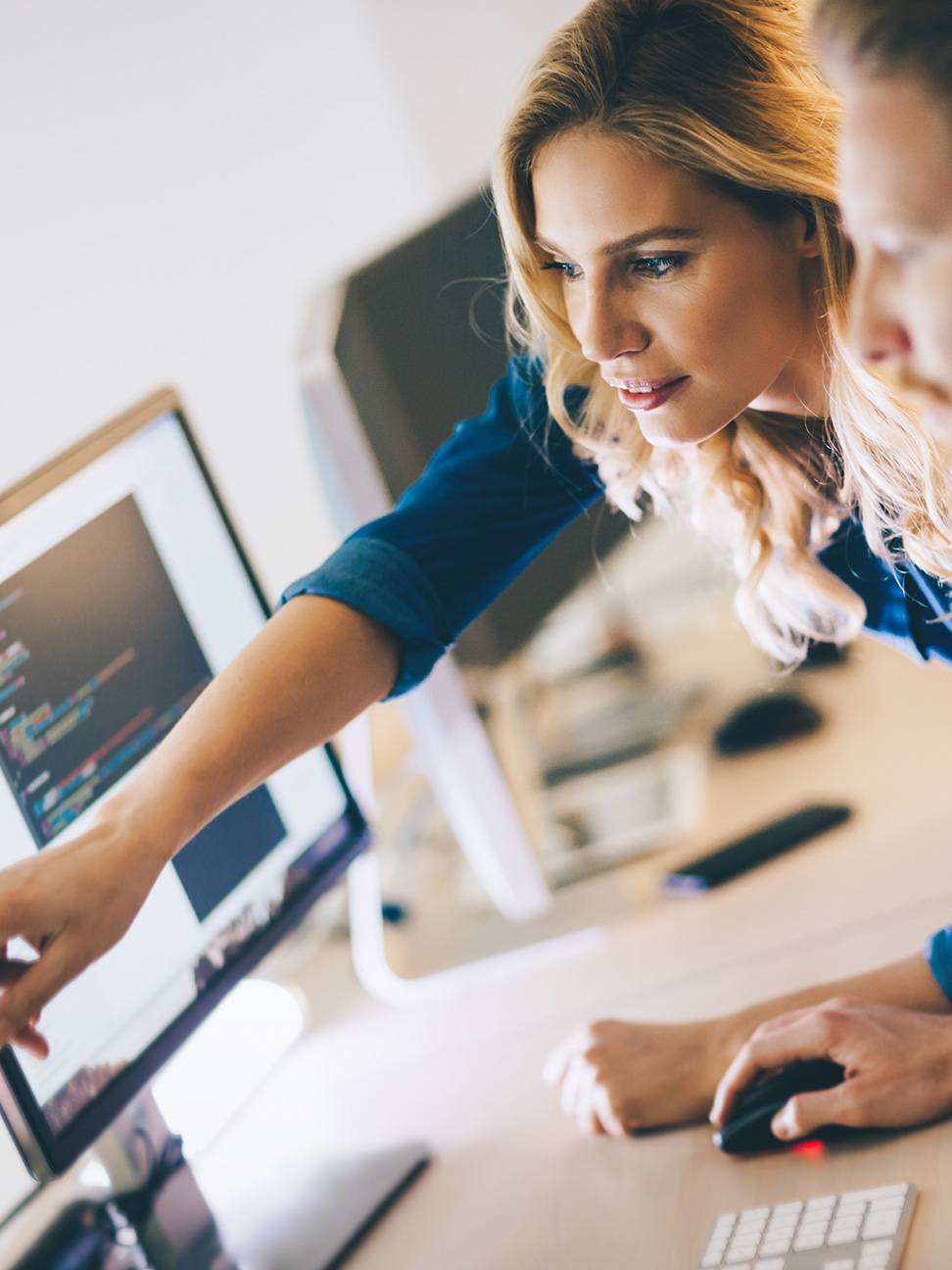 Colleague pointing to content on computer monitor