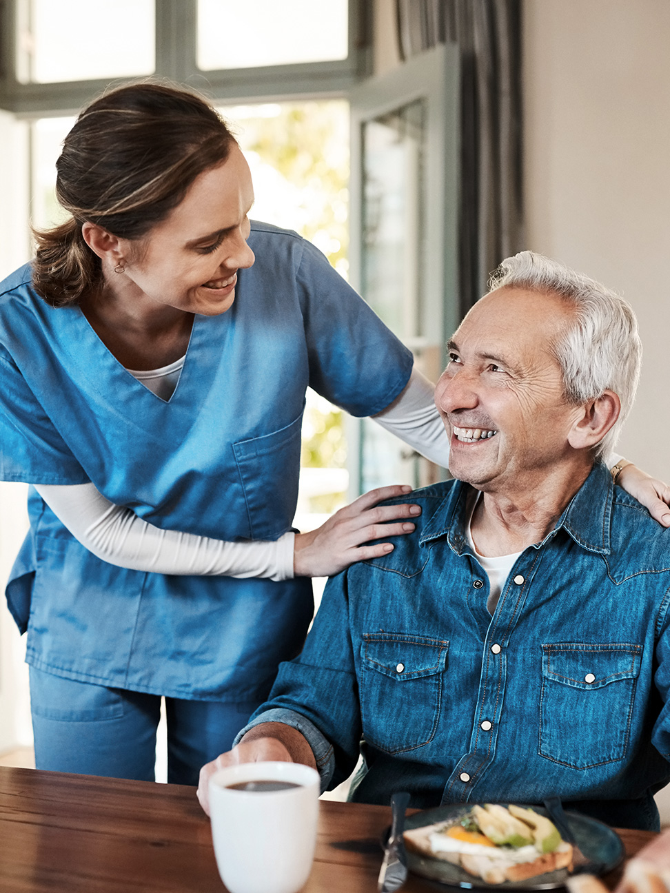 The image shows a healthcare worker greeting a resident in a retirement village. 