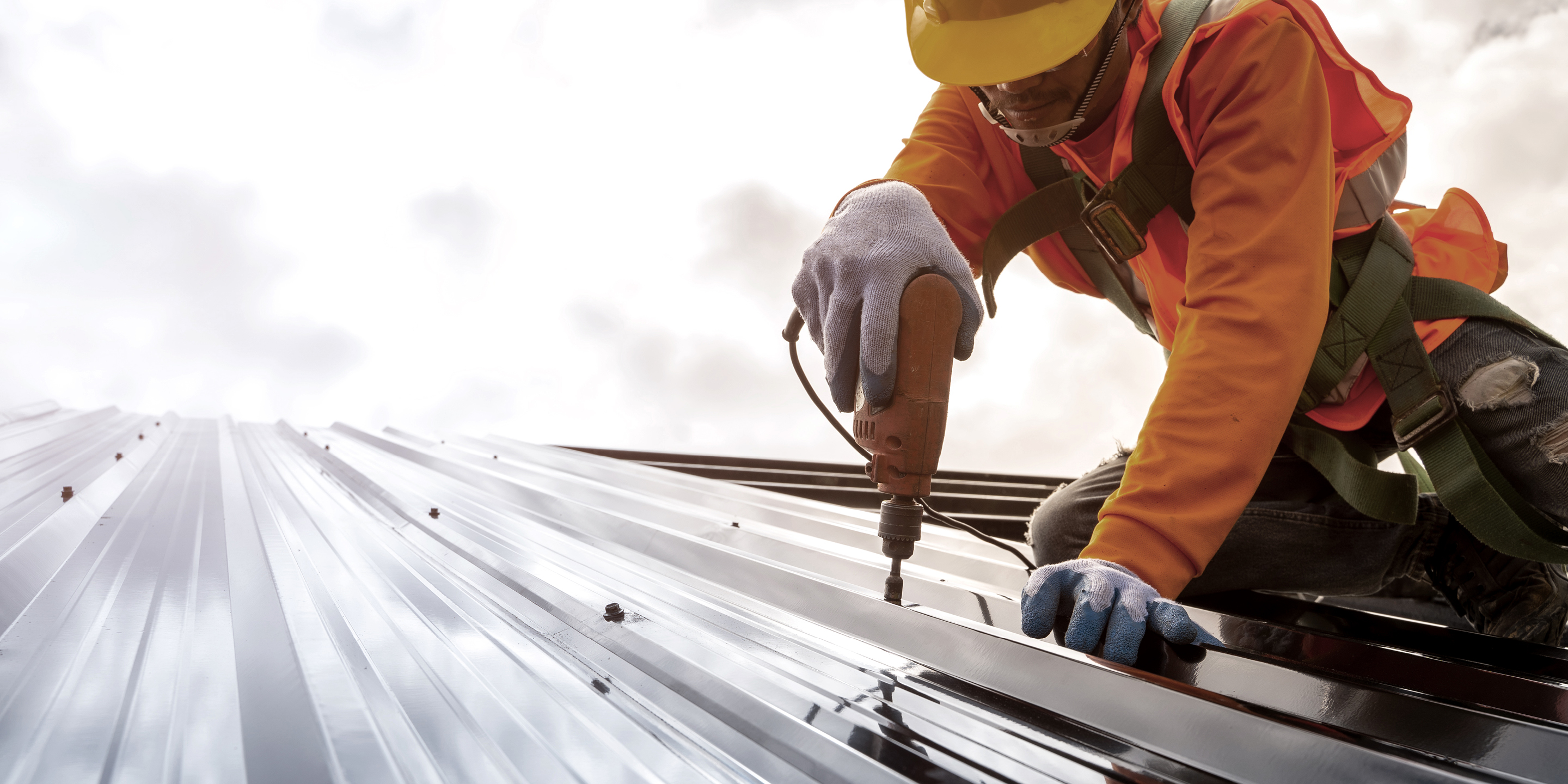 Worker Using Drill On Building