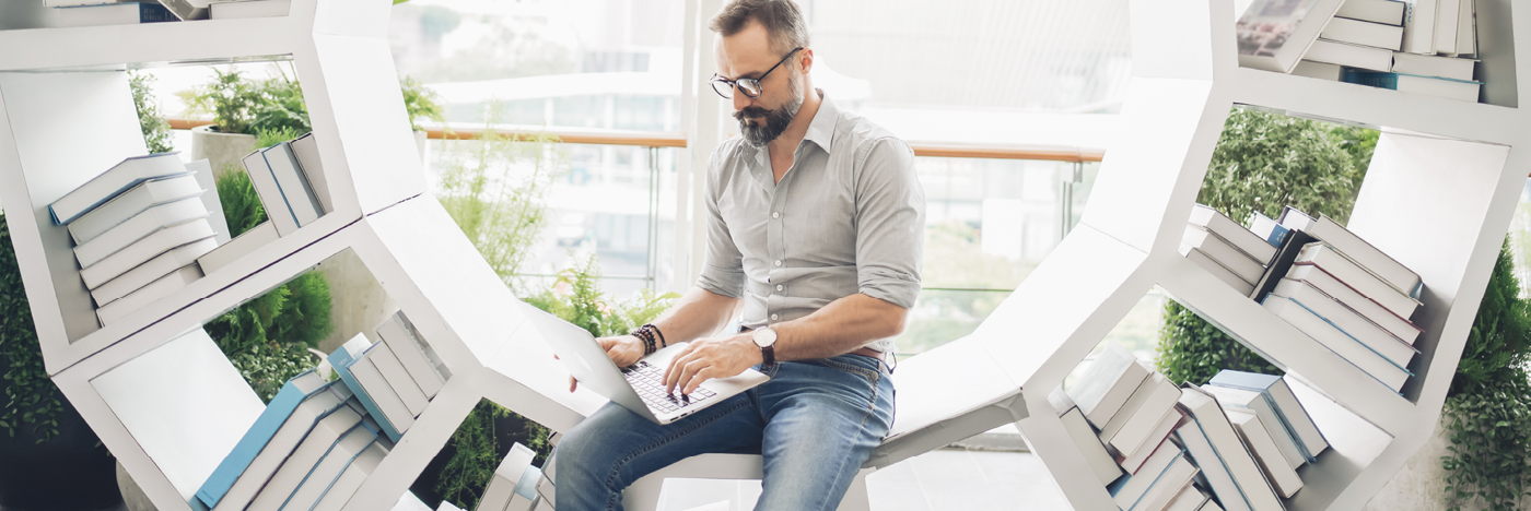 Man working on laptop surrounded by books