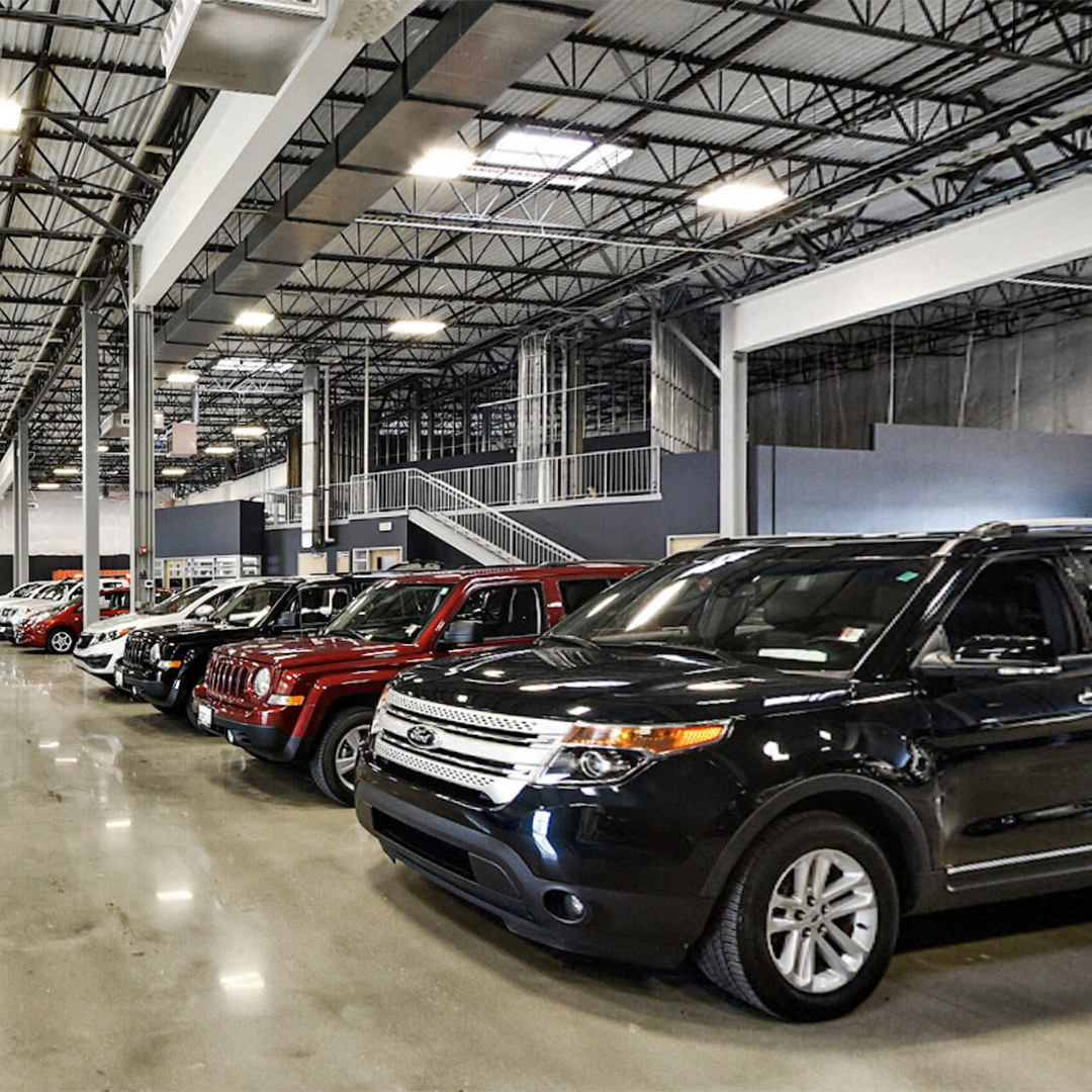 A row of SUVs and trucks parked inside a large, well-lit industrial garage.