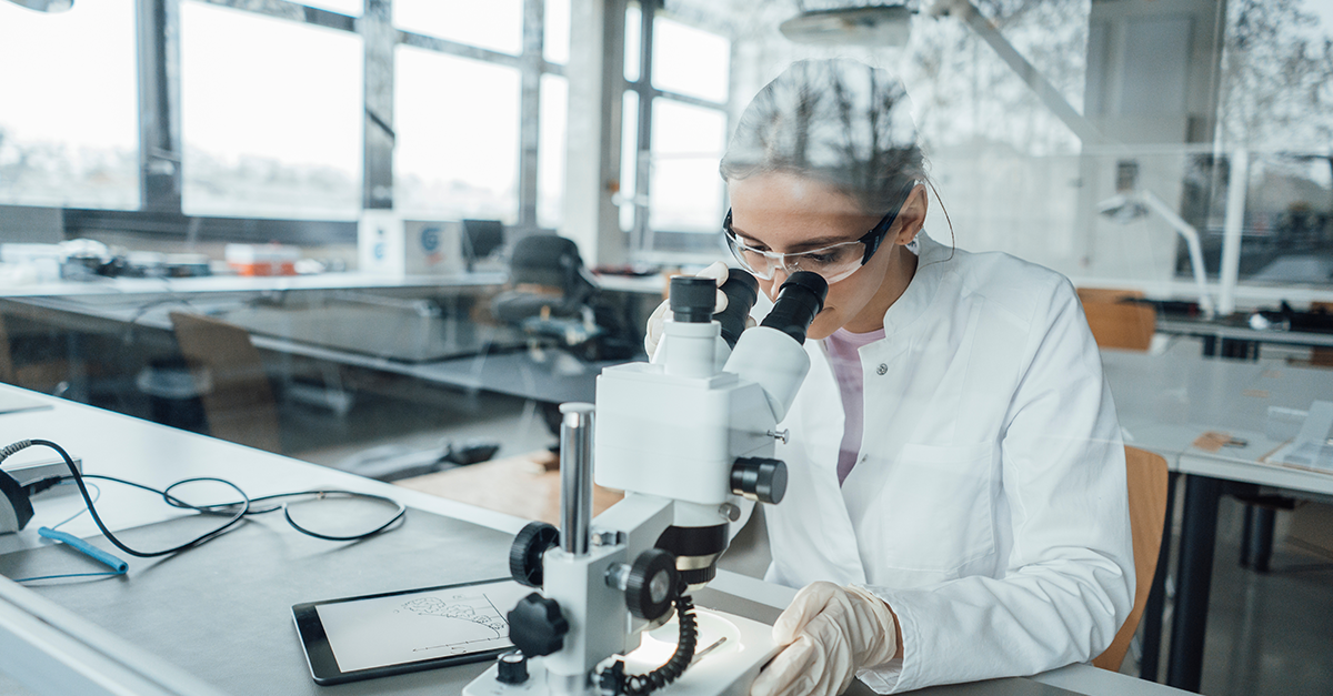 Close-up of a scientist looking through a microscope, conducting laboratory research.