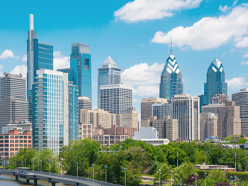 Philadelphia skyline showcasing various commercial high-rises and office buildings, situated along a waterfront park.