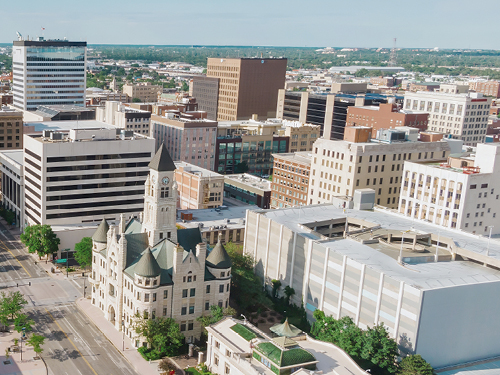 Aerial view of a city's downtown core, showing a mix of modern and historic commercial buildings and a prominent courthouse.