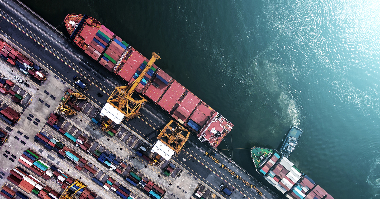 Aerial view of a busy cargo port with container ships and cranes loading and unloading shipping containers.
