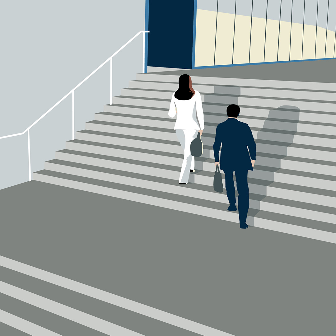 A man and a woman walk up a flight of stairs, carrying briefcases.