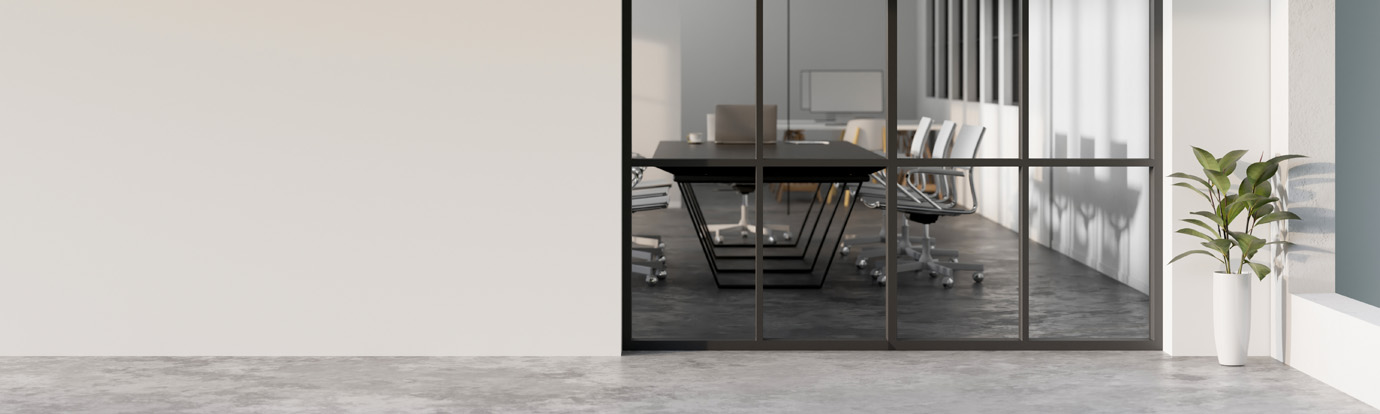 A modern conference room with a large glass door and several chairs around a rectangular table is seen through the entrance. The room has a minimalist design with concrete flooring, and a potted plant is placed near the door.