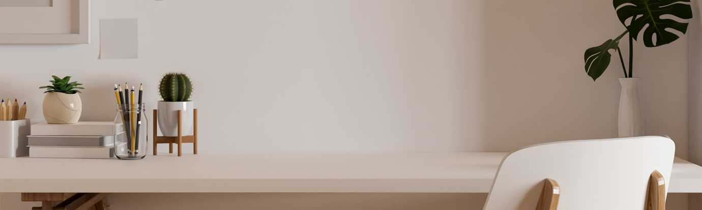 Minimalist white desk with succulents, pencils, books, and a white chair. A monstera leaf sits in a vase on the wall.