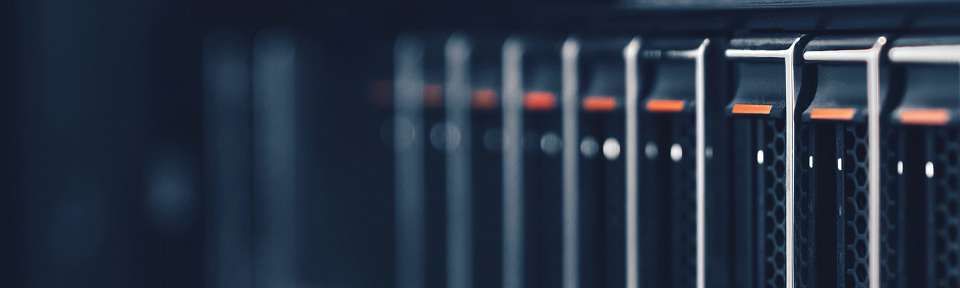 Close-up of a server rack, showing multiple dark-colored server units with orange indicator lights and a detailed textured metal grill.