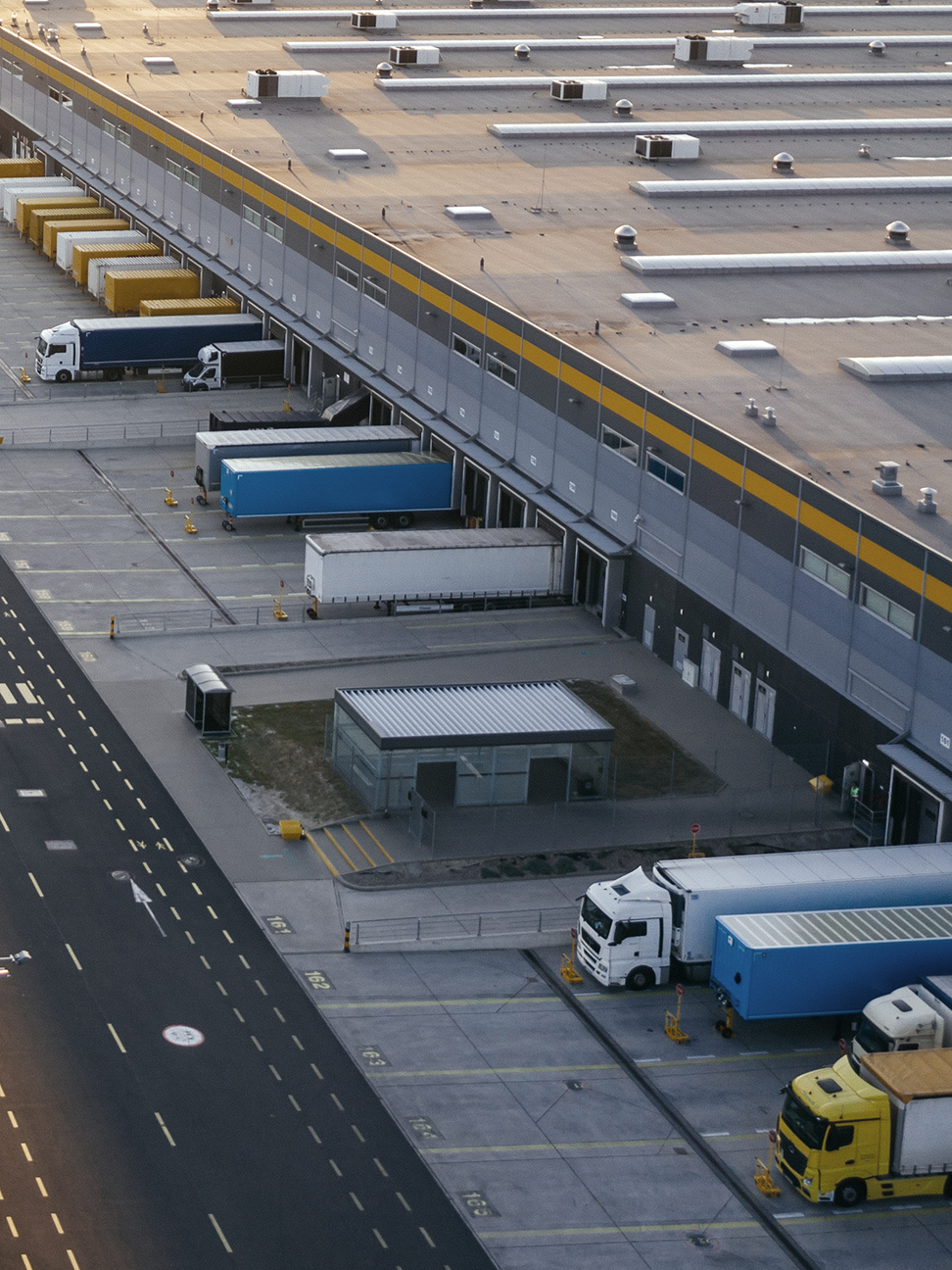 Aerial view of an industrial building with trucks in loading docks