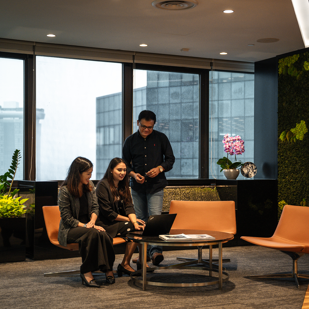 Three people sitting around a coffee table in an office