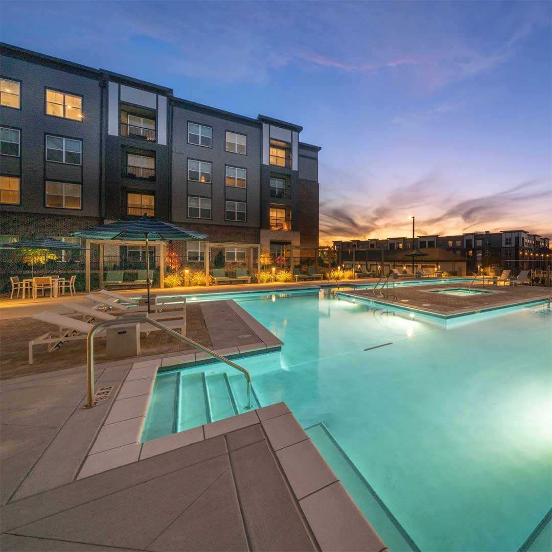 A blue swimming pool in front of a modern apartment building.
