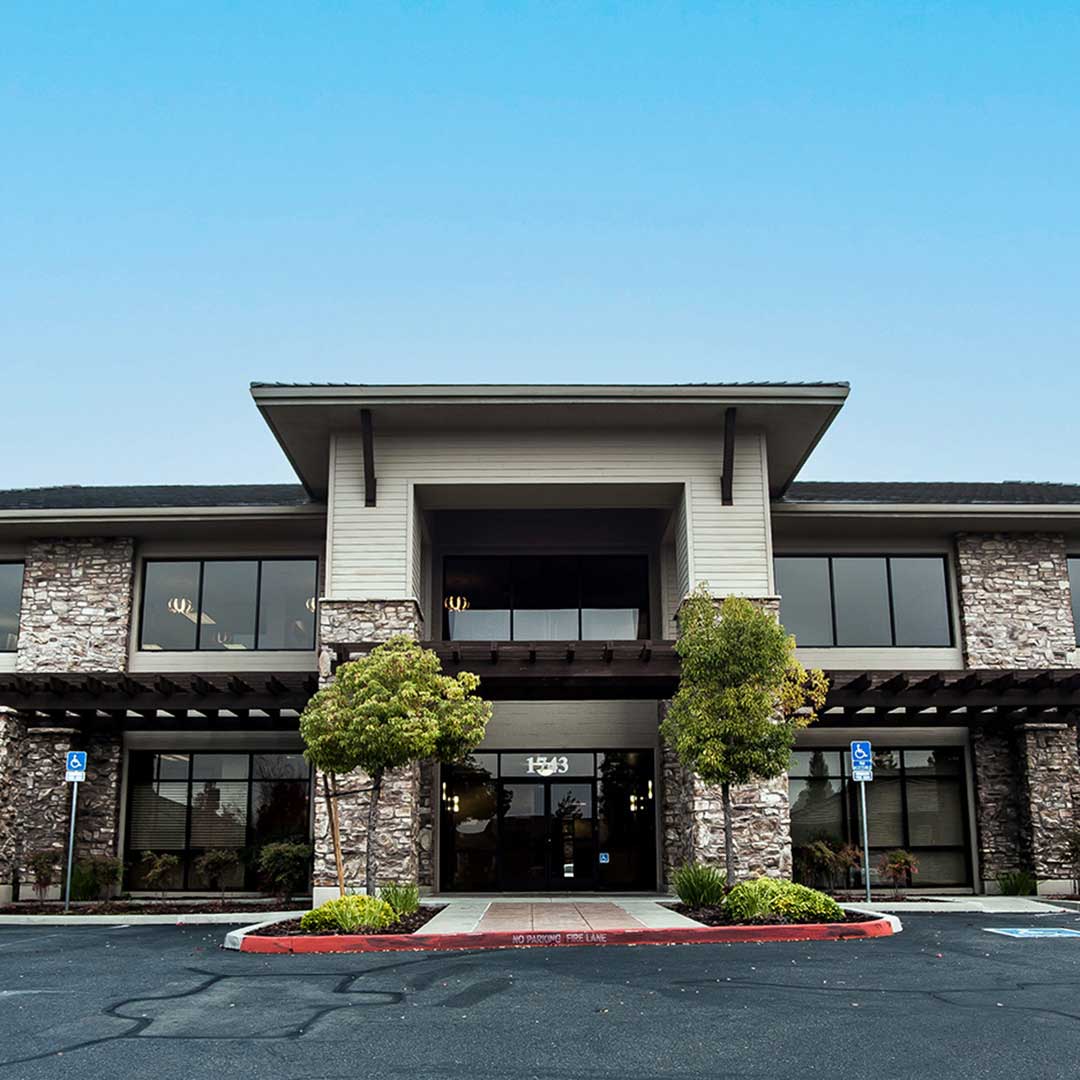 Front entrance of a large office building with glass doors and modern architecture, welcoming visitors.