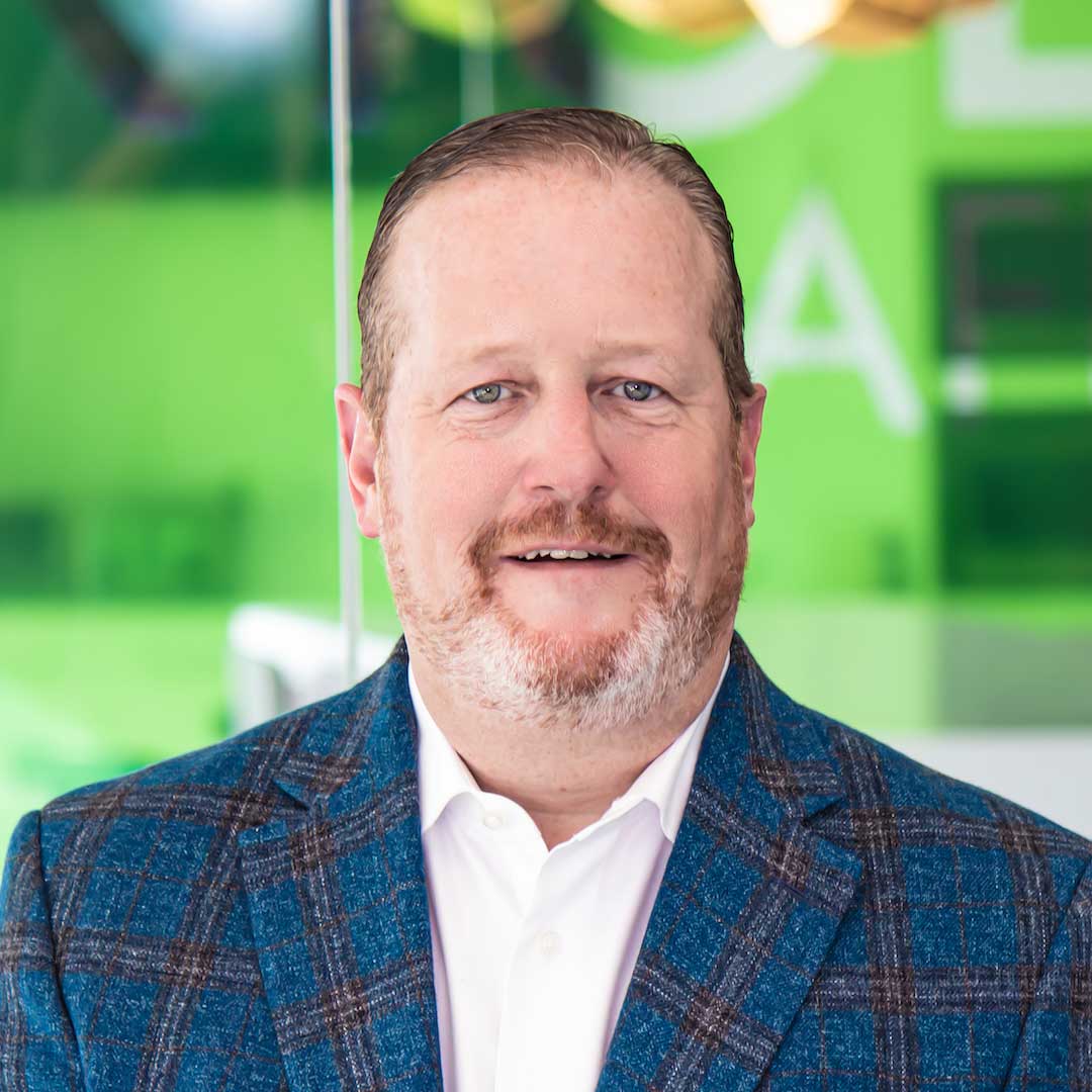 Head shot of Matthew Laraway in a blue suit with a green background