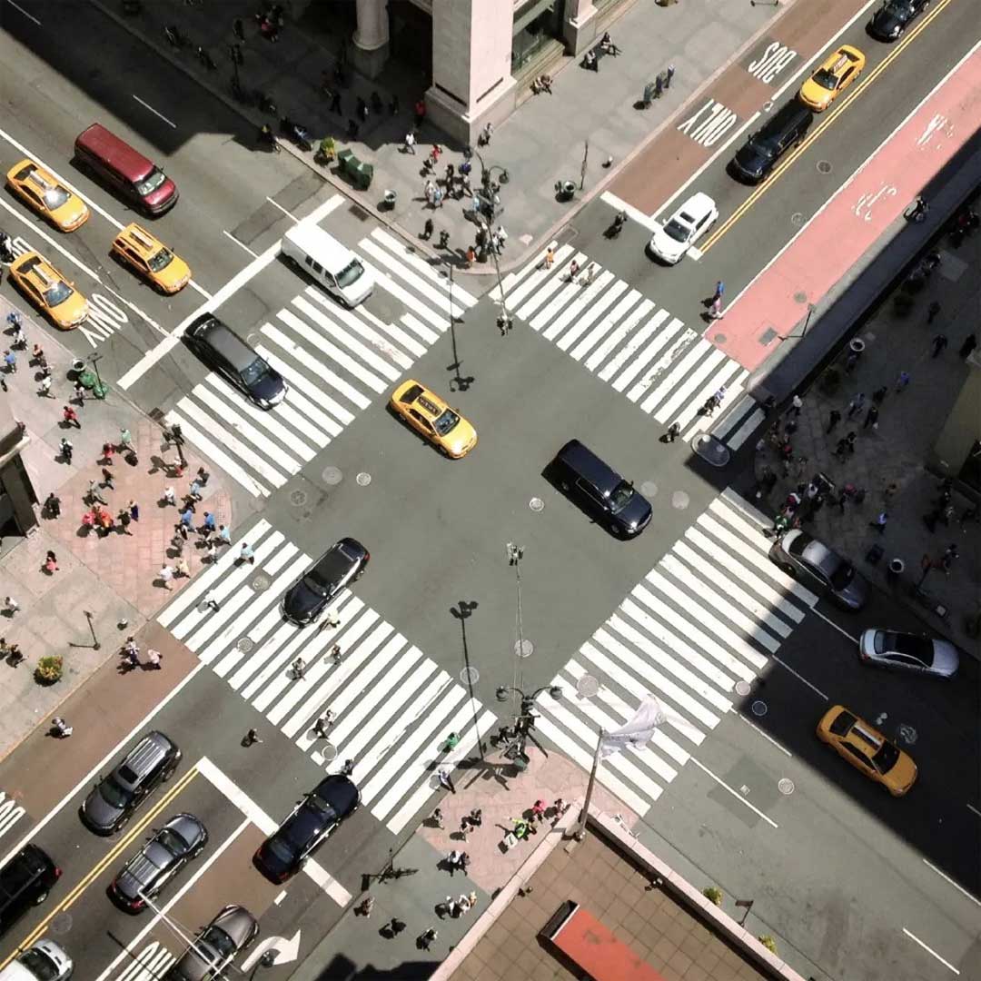 Arial view of a busy intersection during the day with cars and people crossing