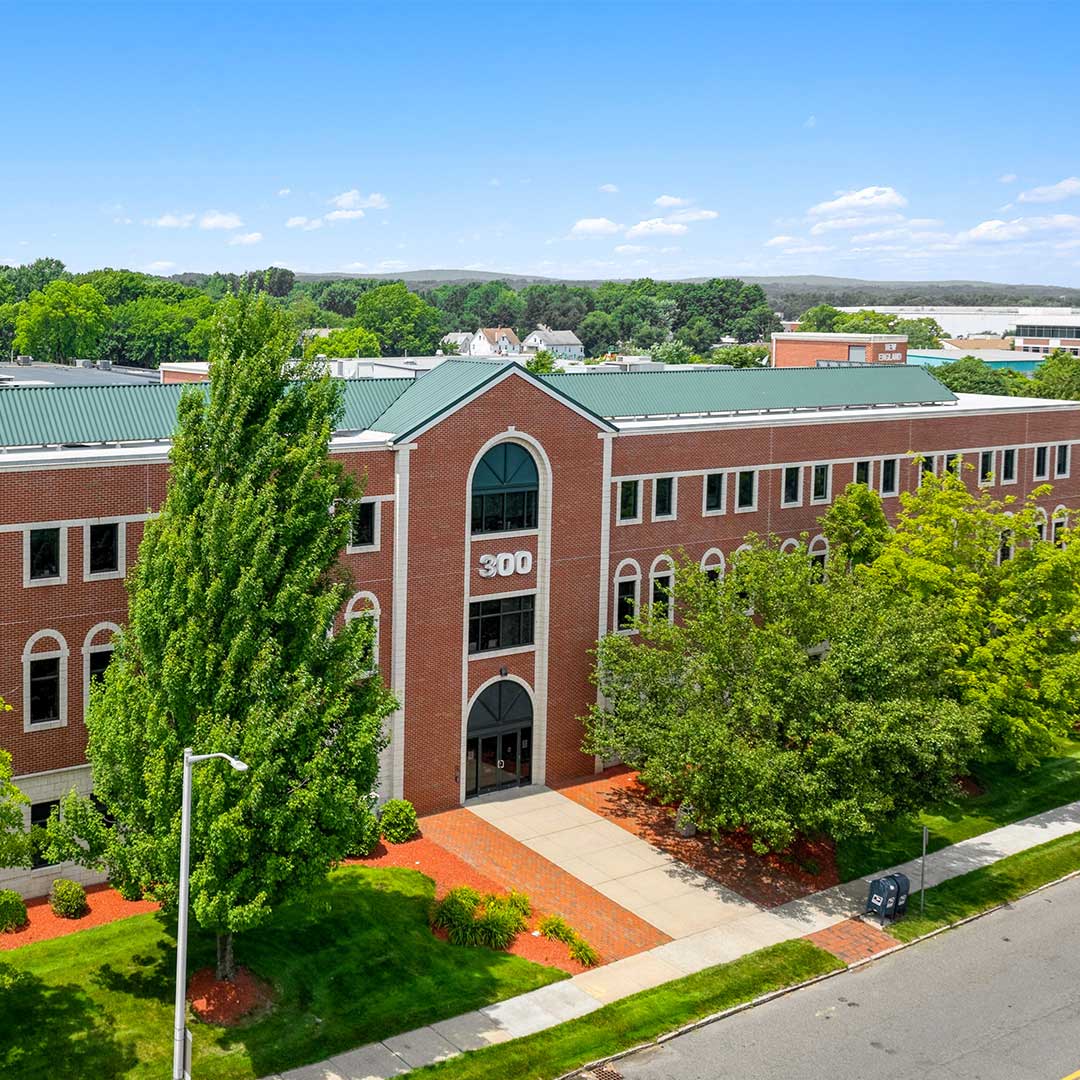 Exterior of red brick medical office building with green pine trees out front