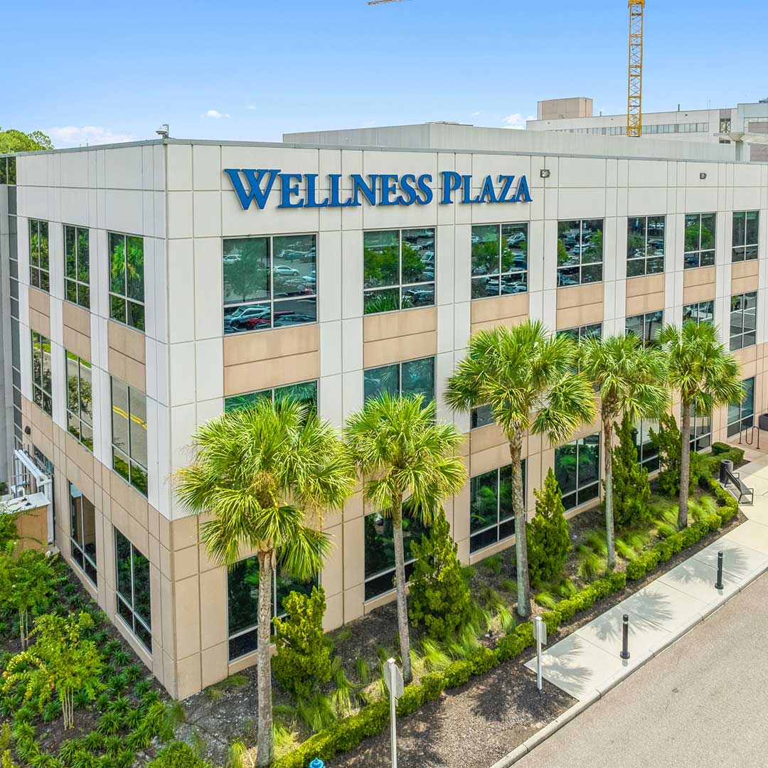 Exterior of Wesley Chapel Wellness Plaza, a medical office building, with palm trees.