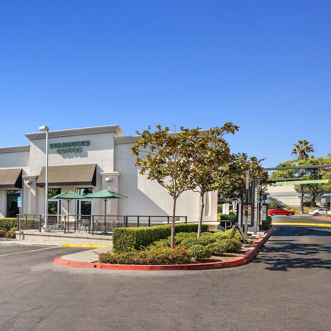 A white building featuring a green awning at its entrance, set against a clear blue sky.