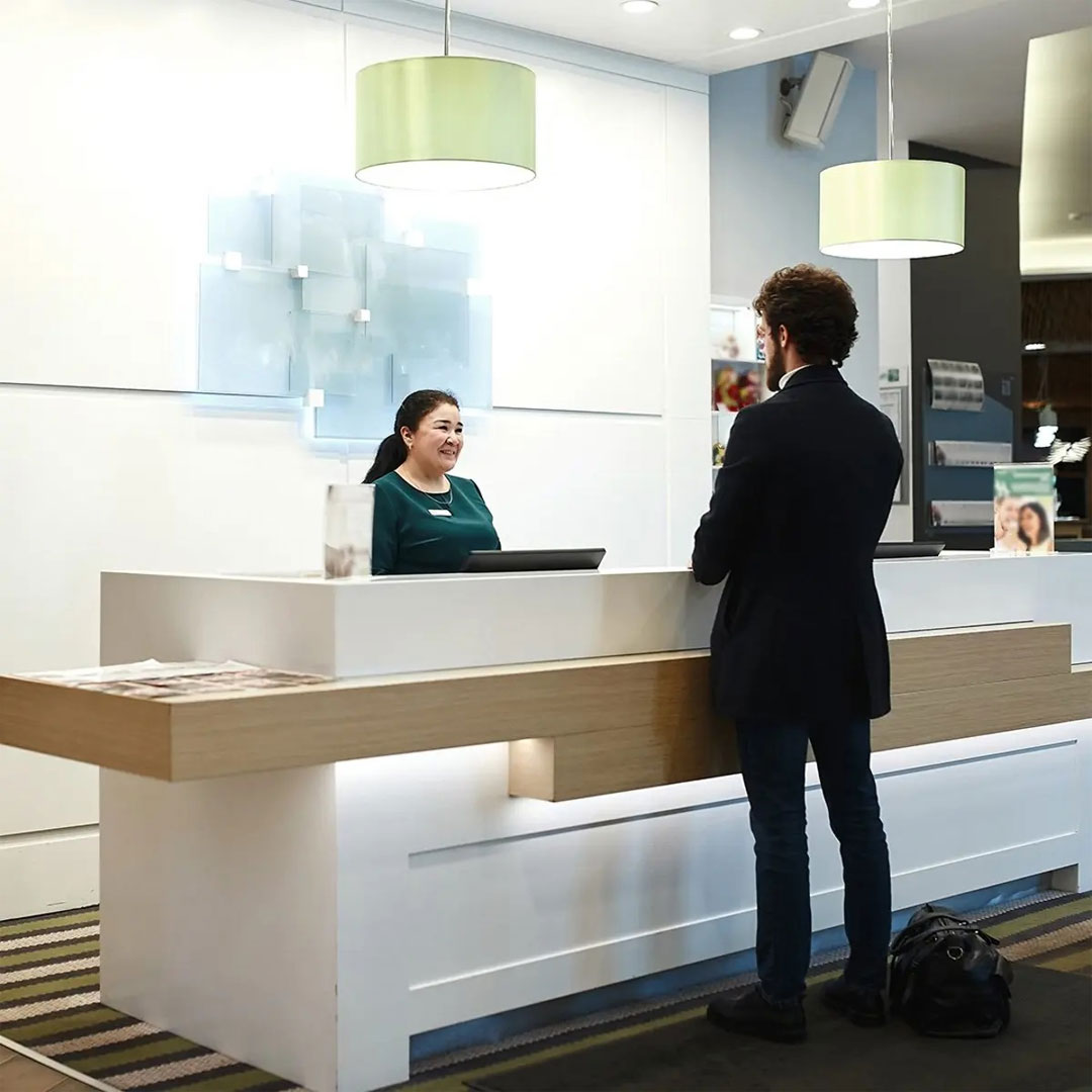 Person checking in at the front desk of a hotel lobby.