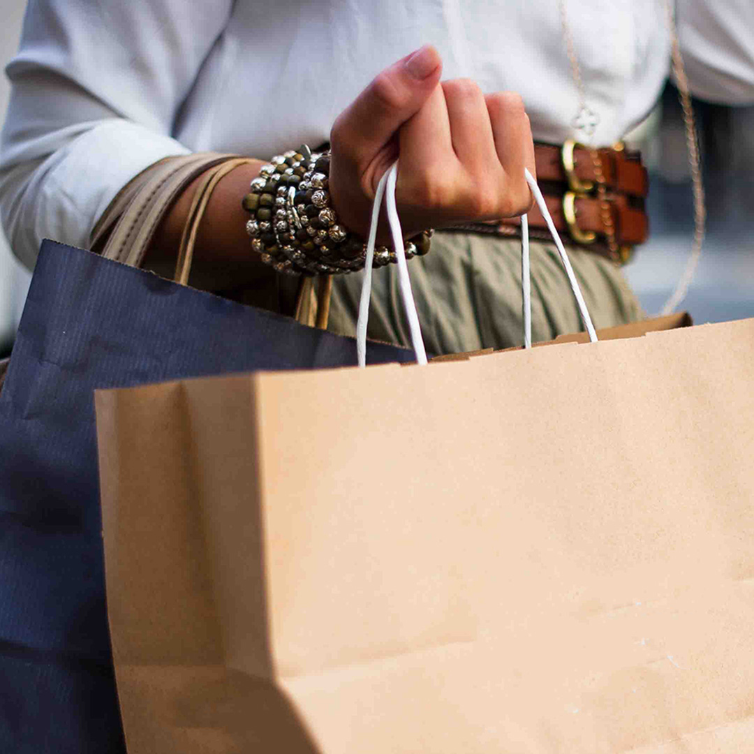 A woman holding two shopping bags in her hands, showcasing her recent purchases.