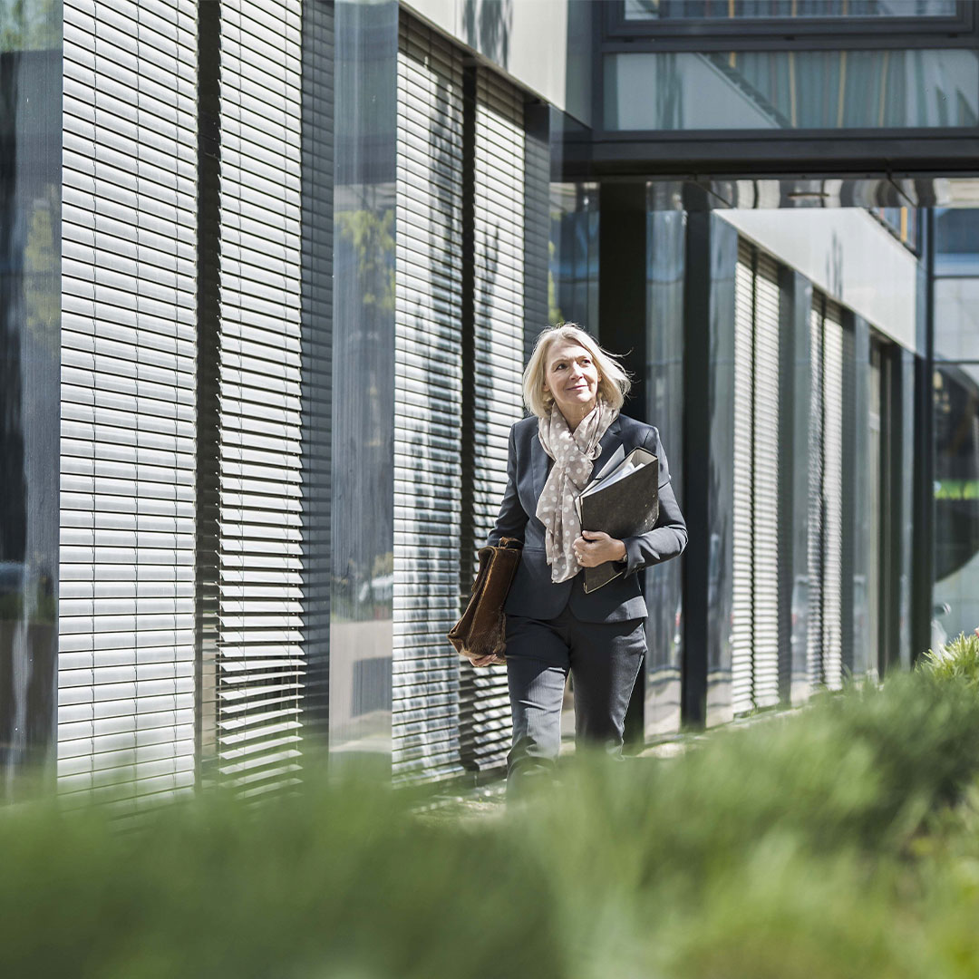 Woman walking outside a sustainble-designed building, showcasing eco-friendly architecture and green building practices.