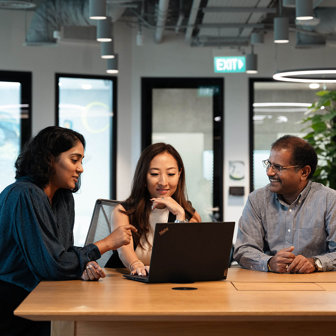 Team of consultants collaborating on sustainability strategy, brainstorming around a computer.